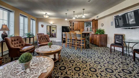 Lounge with armchairs, tables and a kitchen counter.