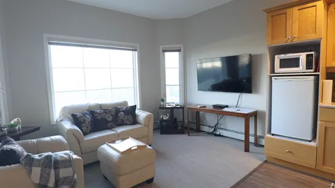 Suite living room with sofas, a television and kitchenette.