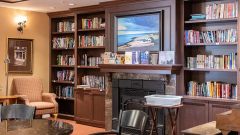 Library seating beside bookshelves and a fireplace.
