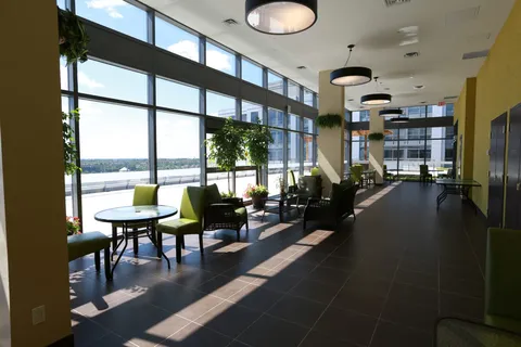 Room with green armchairs, round tables and floor-to-ceiling windows