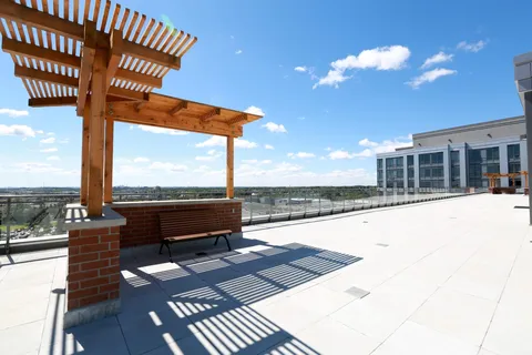 Roof terrace with a wooden pergola, bench and glass railing