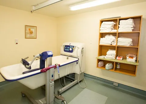 Bathing room with an accessible tub and shelves of towels.