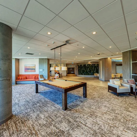 Billiard table beside armchairs and an orange sofa