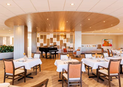Dining room with set tables, a grand piano and wood flooring