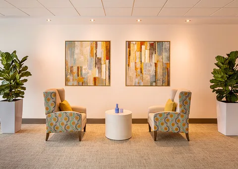 Two patterned armchairs beside a round table and abstract paintings