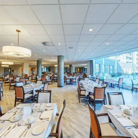 Dining room with set tables and chairs beside tall windows