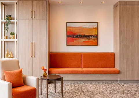 Orange bench seating below an abstract painting