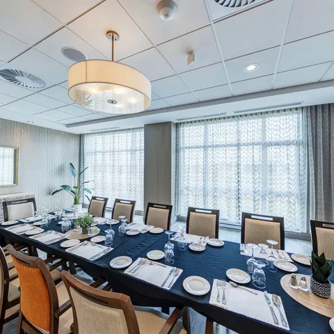 Private dining table set with dishes and glasses beside windows