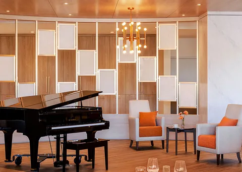 Grand piano beside armchairs and a wood-panelled wall