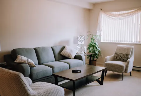 Sitting area with a sofa, armchairs, coffee table and window.