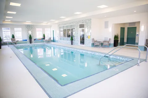 Indoor swimming pool with steps, handrails and chairs along the windows