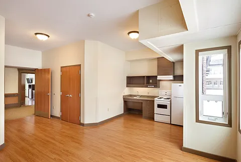 Empty room with a kitchenette, wood flooring and large windows