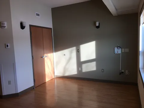 Empty room with wood flooring and sunlight on a grey wall