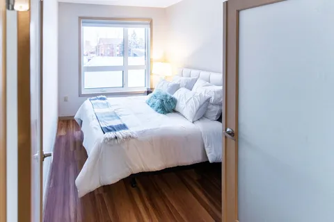 Bedroom with white bedding, a padded headboard and a window