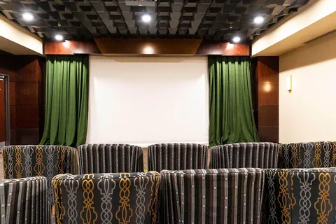 Striped theatre seats facing a blank screen with green curtains