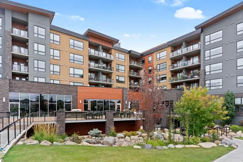 Balconied residence above a patio, landscaped rocks, shrubs and lawn