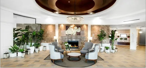 Circular lobby with armchairs, a stone fireplace and potted plants