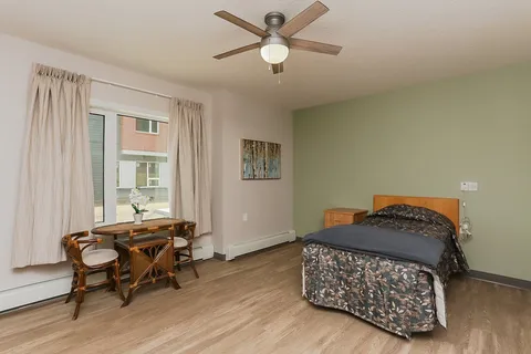 Bedroom with a single bed, a small table and wooden drawers