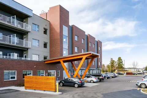 Balconies and a timber entrance canopy beside a parking area