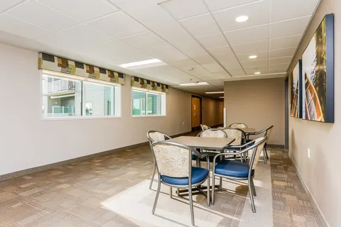 Tables and blue upholstered chairs beside windows and landscape artwork