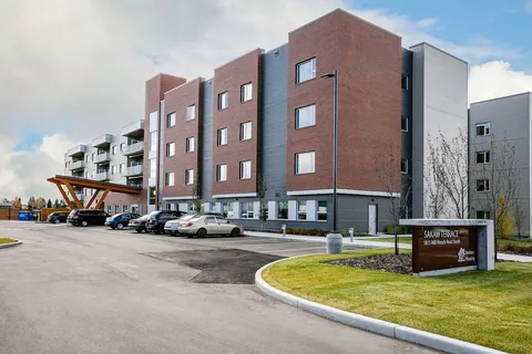 Brick and grey residence beside a curved driveway and parked cars