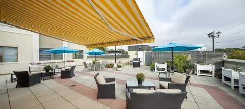 Rooftop patio with tables, chairs, planters and yellow striped awnings