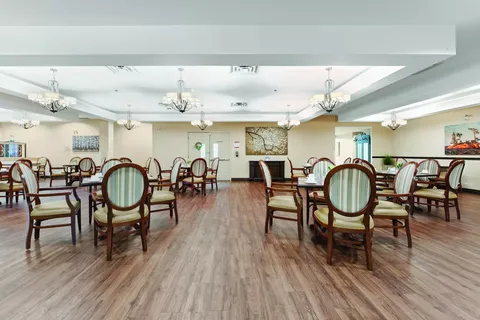 Dining room with oval-backed chairs, set tables and chandeliers