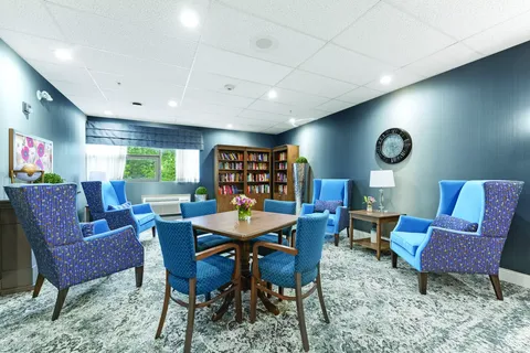 Library with blue armchairs, bookshelves and a wooden table