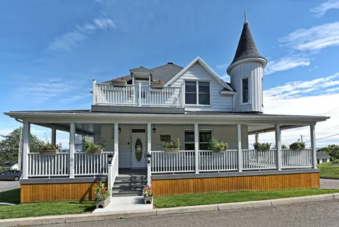 Front of a white residence with a covered porch, black roof and flower planters