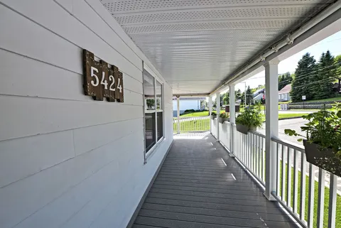 Covered wooden porch with white railings and flower planters