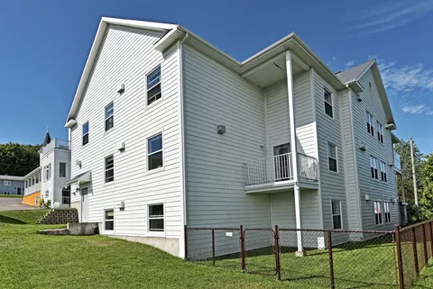 White multi-storey building beside a lawn and chain-link fence