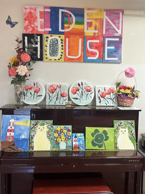 Upright piano displaying colourful paintings of flowers and buildings