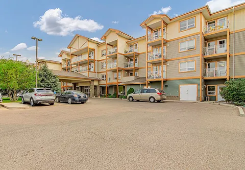Multi-storey building with balconies, a covered entrance and parked cars