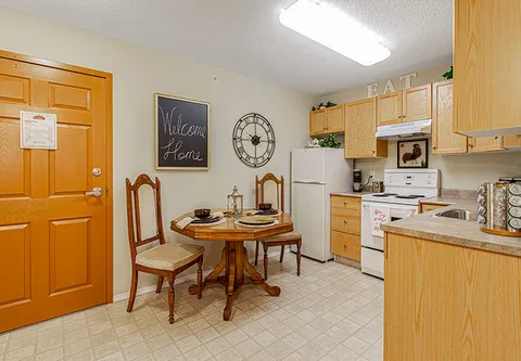Kitchen with wooden cupboards, a refrigerator, stove and small dining table