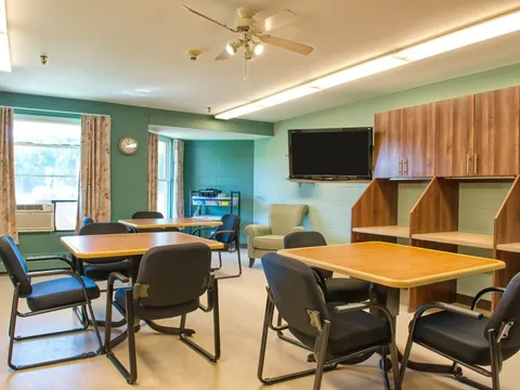 Room with tables, chairs, cabinets and a wall-mounted television