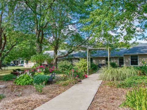 Garden path with flowering plants and trees beside a single-storey building