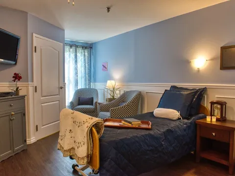 Bedroom with a single bed, two armchairs and a wall-mounted television