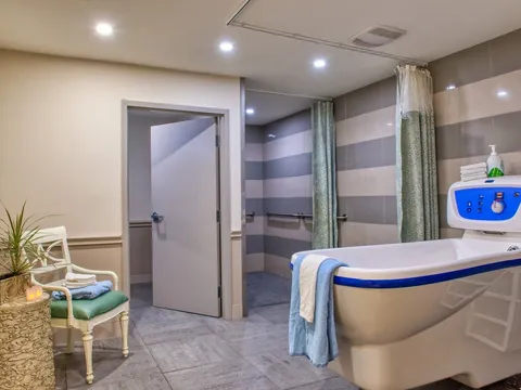 Bathroom with a bathing tub, chair and striped wall tiles