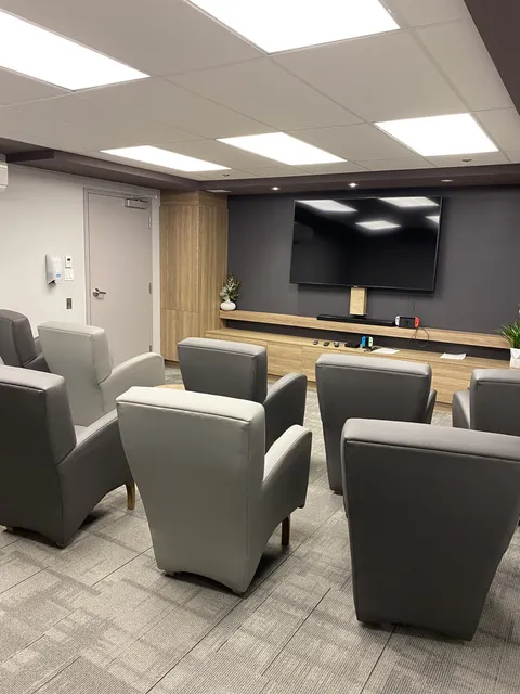 Television lounge with armchairs and small tables.