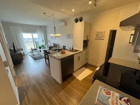 Apartment kitchen and dining area with wood flooring.