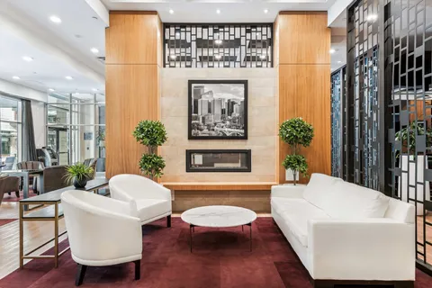 Lobby seating arranged around a stone fireplace and wooden wall panels.