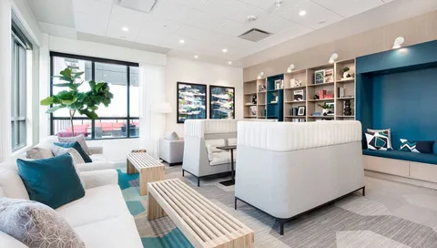 Library lounge with sofas, bookshelves and tall windows.