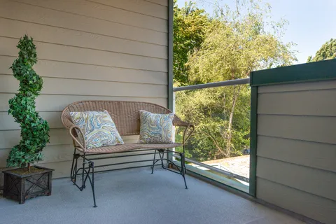 Balcony with wicker seating and a small table.