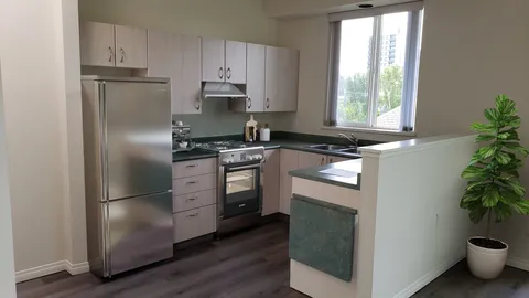 Suite kitchen with white cabinets, stainless appliances and a window.