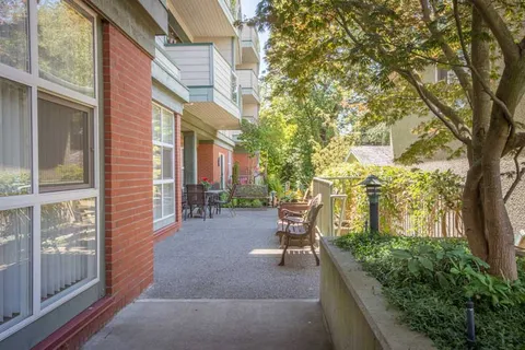 Paved walkway with benches and planting beside the building.