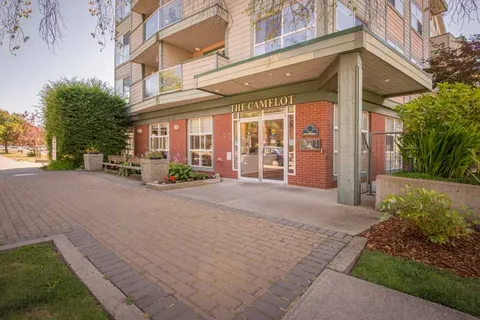 Glass entrance doors beneath the building and a paved forecourt.