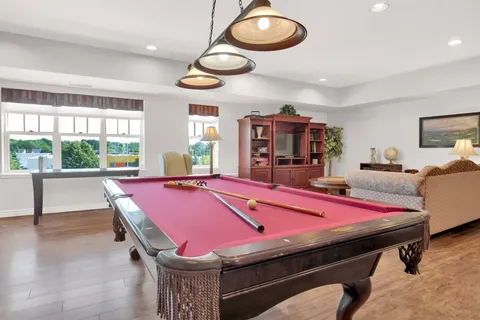 Pool table in a room with large windows and a wooden cabinet