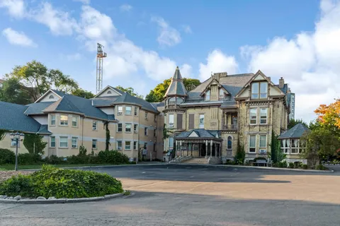 Stone and stucco residence with a turret, covered entrance and landscaped circular driveway