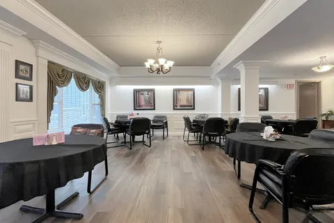 Dining room with round tables, black chairs and chandeliers.