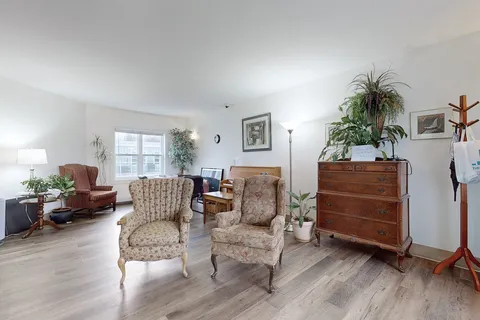 Lounge with upholstered armchairs, a piano and storage furniture.